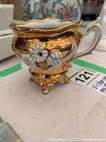Gilt Victorian moustache cup with floral decoration, showing full side view including handle and footed base.