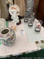 Angel figurine, hand figurine, floral vase, and four drinking glasses on table