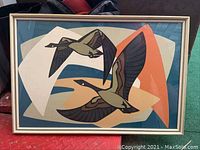 Framed print showing two loons flying with abstract background, frame has visible wear.