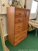 Front and angle view of wood grain MDF armoire showing six drawers, one door with wood trim, and overall condition.