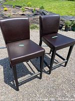 Two brown leather chairs photographed outdoors on gravel, showing front and side views to highlight condition and style.