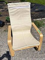 Front view of IKEA Poang chair showing beige fabric cover with visible soiling and broken zipper at headrest area, light wood bentwood frame.