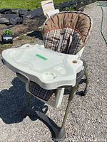 Full view of Evenflo Easy Fold high chair with plaid seat and beige tray showing some missing pieces.