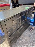 Front and angled view of wooden sideboard with multiple drawers and cabinet doors, dark finish, showing general wear and metal handles.