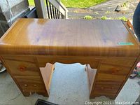 Image of maple veneer vanity desk with waterfall edge design, drawers on both sides, and visible wear and missing veneer on left front foot.