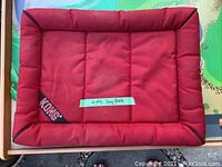 Red Kong small rectangular dog bed, quilted padded design, with Kong logo tag on corner, showing some dirt and in need of cleaning.