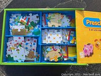 Top view of the opened puzzle box showing separated puzzle pieces in sections inside a divided tray.