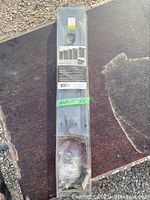 Curtain rod in original sealed packaging, placed on a wooden surface outdoors.