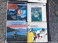 Eight vinyl record album covers shown outdoors on the ground. Includes Glasgow Phoenix Choir, The World of Christmas from Trinity College Choir, Kirkintilloch Children's Choir, and Half A Sixpence soundtrack.