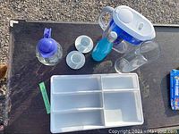 Photo of the drawer organizer, espresso cups and saucers, blue insulated bottle, PUR water pitcher and clear glass bottle with blue lid on black surface.