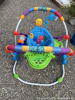 Front view of the Baby Einstein Jumperoo showing colorful padded bars, blue fabric seat with ladybug design, and attached sun toy on frame.