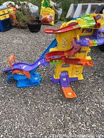 Large multi-level VTech Go Go Smart Wheels racing track set with ramps and slides on gravel ground