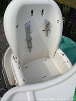 White Graco high chair seat from the front showing adjustable straps attached to the backrest, missing seat cover and waist belt.