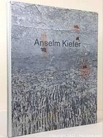 Front cover of hardcover art book "Anselm Kiefer" with textured design and black text on gray cracked-stone background.