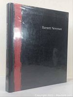 Front and spine view showing black dust jacket with red vertical stripe and white 'Barnett Newman' text.