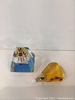 Perfume bottle base and yellow glass dabber shown separately on white background