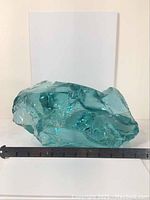 Front view showing size context with ruler, dimensions approx. 13 inches long, irregular shape and aquamarine color