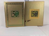 Front covers of The Hobbit 50th Anniversary Edition book and original slipcase, showing gold texturing and anniversary logos