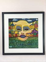 Full view of the framed square print showing the colorful face and buildings.