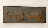 Top view of vintage metal printing plate showing engraved reindeer design in relief with some rust and wear.