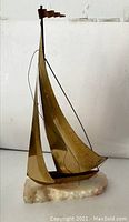 Frontal image of the large brass sailboat figure mounted on a solid onyx base showing the entire piece against a plain background.