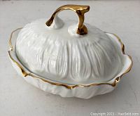 Photo of vintage white ceramic covered dish with gold trim and lid handle, showing detailed texture.
