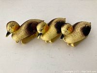 Three vintage plastic baby duck decoys arranged side by side, showing detailed paint and shape.