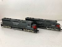 Two vintage Southern Pacific toy train engines side by side on a white background showing both in profile.
