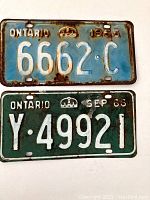 Photo of two vintage Ontario license plates from 1965 (green) and 1966 (blue), showing front side with embossed numbers and letters, rust and wear.