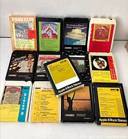 Photo showing front side of 13 assorted 8 track cassette tapes with various album covers and labels visible