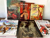 Six hardcover books with dust jackets on Vikings, mythology, ancient history, and the Middle Ages arranged on a flat surface.
