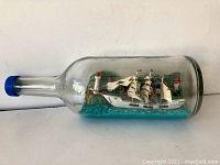 Full side view of the ship and island inside the bottle, showing the lighthouses and water effect.