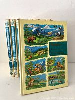 Set of three hardcover books shown from front angled view revealing illustrated wildlife scene covers mainly focusing on mammals and natural landscapes.