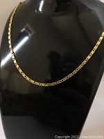 Close-up photo of the 18K yellow gold plated necklace displayed on a black mannequin bust, showing the unique link chain design.