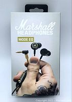 Front view of the sealed retail box showing Marshall Mode EQ ear bud earphones with hand holding earbuds and angled gold 3.5mm plug on white background.