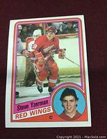 Front of 1984 Topps Hockey #49 Steve Yzerman Rookie Card showing player in Red Wings uniform skating on ice and portrait at bottom right.