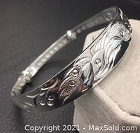 Front view of silver bangle with detailed dragon and phoenix design