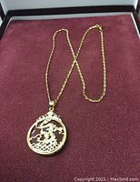 Full view of the gold chain necklace with circular pendant showing the gold dragon mount.