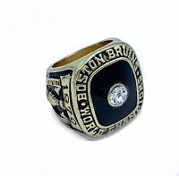 Front angle of the gold-tone ring showcasing black enamel face and central clear gemstone, with inscription 'BOSTON BRUINS WORLD CHAMPIONS' on bezel.