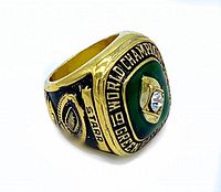 Side angled view of gold-tone ring with engraving 'STARR' and football design.