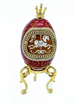 Closed view of red enamel egg with gold swirl decoration, crown top, and pearl trim on gold stand.