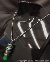 Front view of the pendant showing green jade cylinder wrapped with detailed silver Asian dragon, hanging on silver beaded chain.