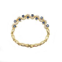 Top view of gold plated bracelet with blue and white stones arranged in alternating pattern.