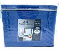 Packaged blue 4 piece bed sheet set from Luxe Maison Luxueuse brand in clear plastic zip bag.