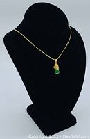 Necklace displayed on black velvet bust stand, showing chain and pendant in profile.