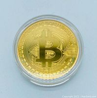 Front side of the gold plated 2020 Bitcoin coin with embossed Bitcoin symbol and surrounding circuit pattern.