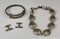 Photo of sterling silver cuff bracelet, cufflinks, and floral motif choker necklace.