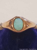 Close-up front view of ring showing oval opal set in gold band