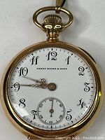 Front view of white enamel dial with Arabic numerals and Henry Birks & Sons signature