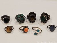 Front view of all seven rings showing variety of semi-precious stones and silver settings.